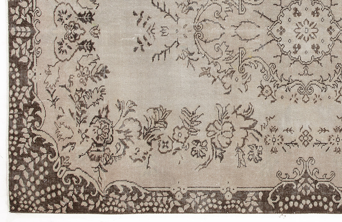 Taupe and dark brown rug with a traditional floral medallion pattern and ornate border.