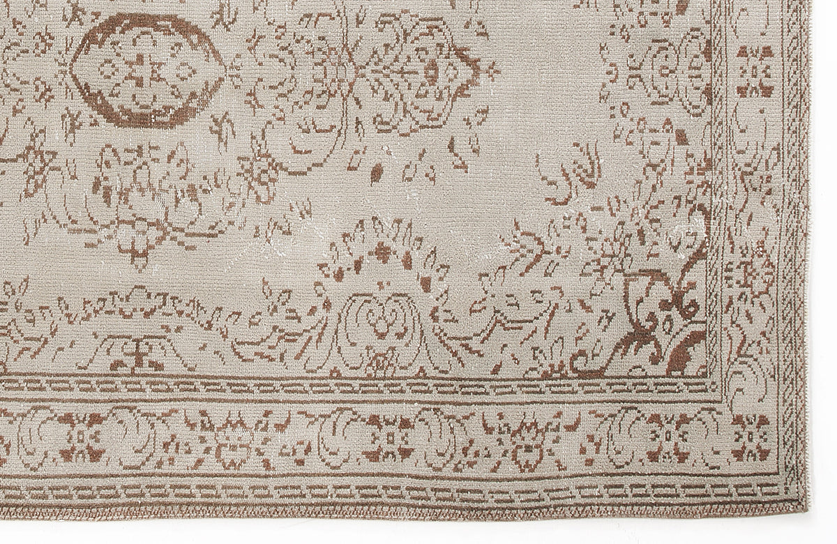 Beige and brown rug with a distressed traditional floral medallion pattern and a geometric border.