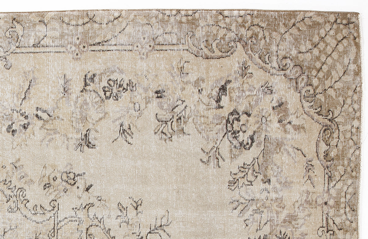 Beige and taupe distressed rug with a faded floral medallion pattern and intricate border detail.
