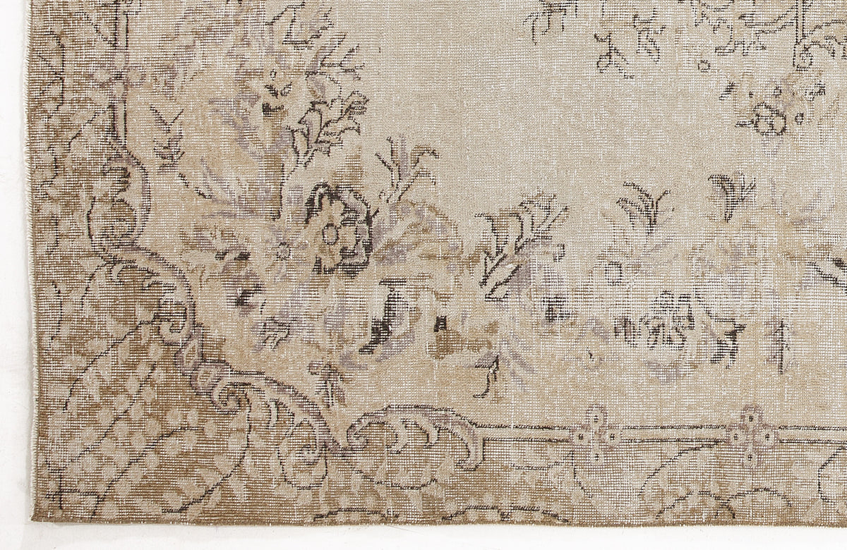 Beige and taupe distressed rug with a faded floral medallion pattern and intricate border detail.