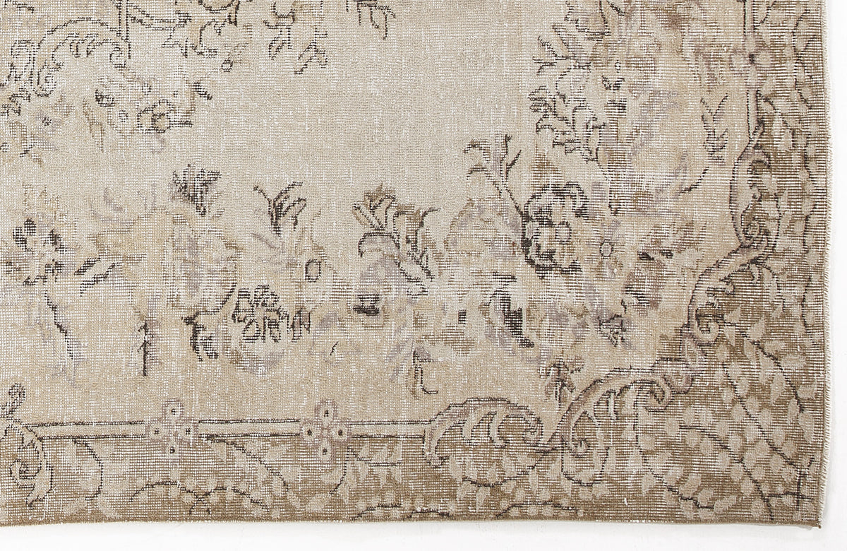 Beige and taupe vintage-style rug with a distressed floral medallion pattern and a detailed border.