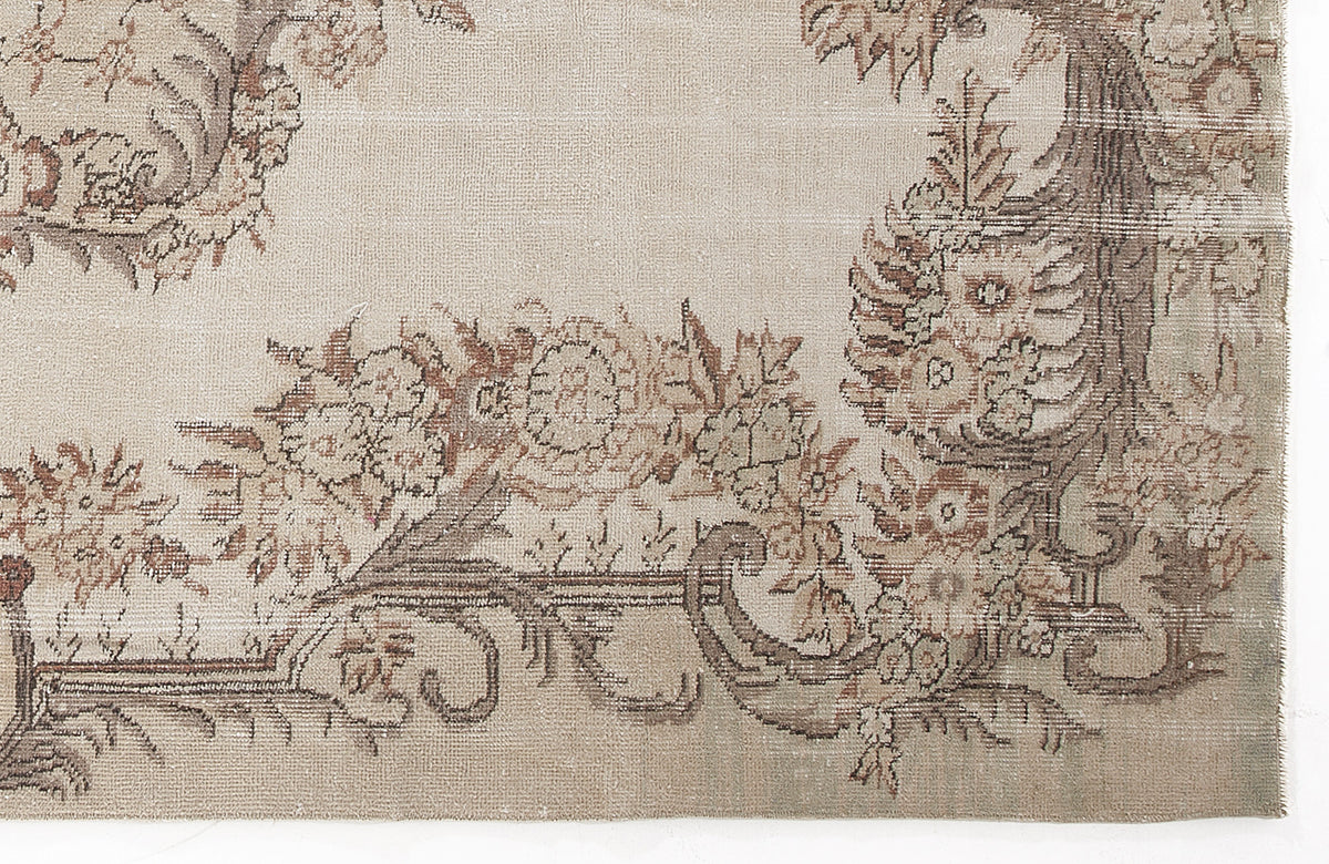 Beige and taupe vintage-style rug with a distressed floral border pattern on a white background.