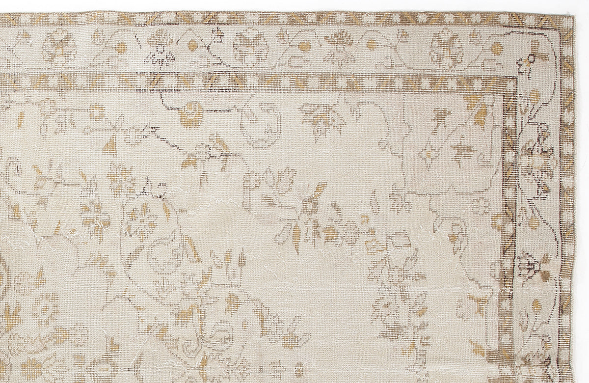 Beige and tan rug with a faded floral pattern and a geometric border on a white background.