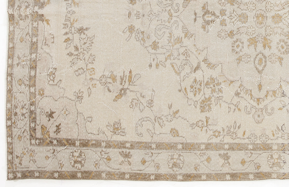 Beige and tan distressed rug with a faded floral medallion pattern and a geometric border.