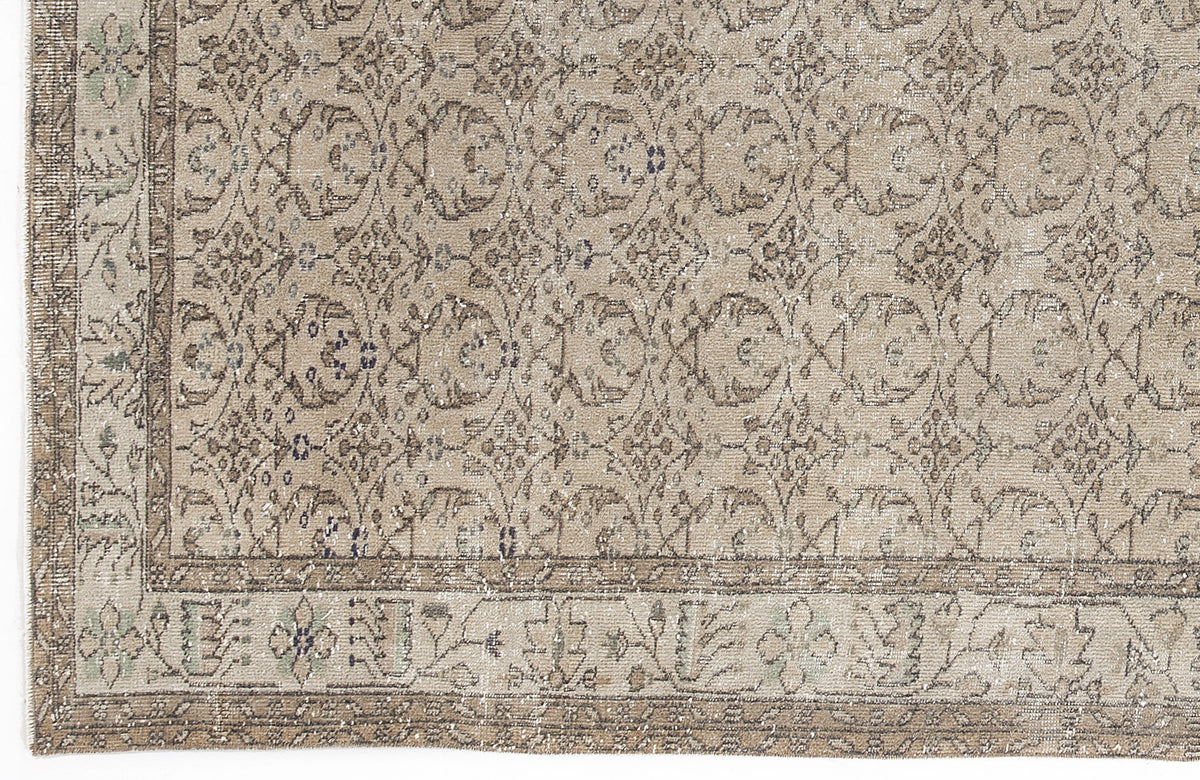 Beige and taupe distressed rug with a repeating floral medallion pattern and a decorative border.