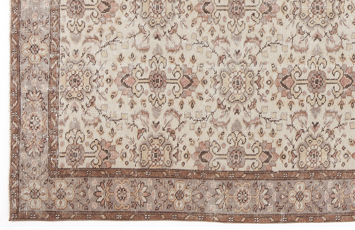 Beige and muted rose vintage-style rug with a distressed floral medallion pattern and a wide decorative border.