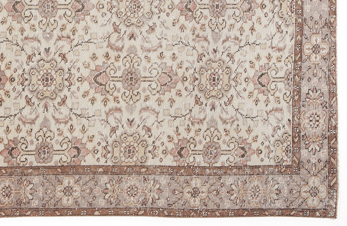 Beige and muted rose vintage-style rug with a distressed floral medallion pattern and a decorative border.