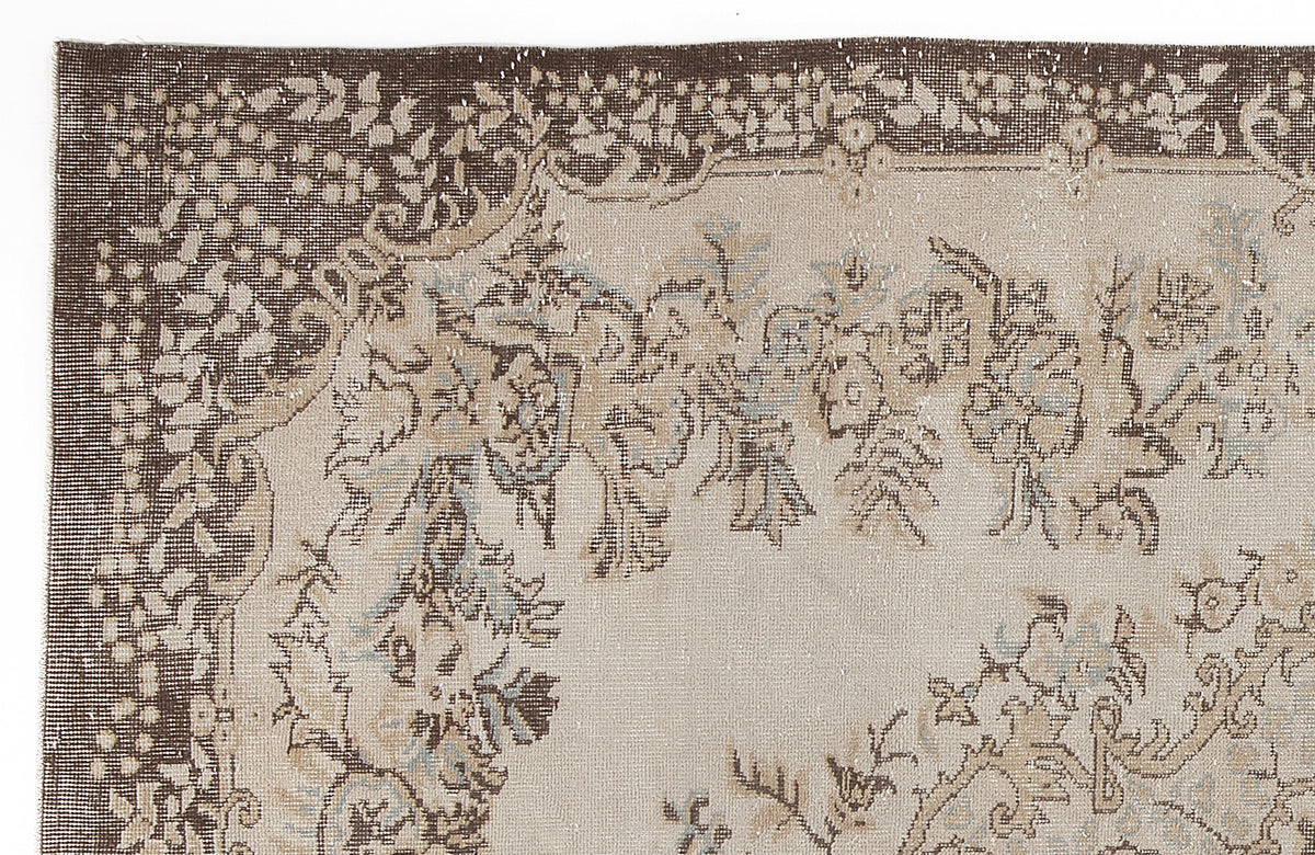 Brown and beige vintage-style rug with a distressed floral border and central botanical motif.