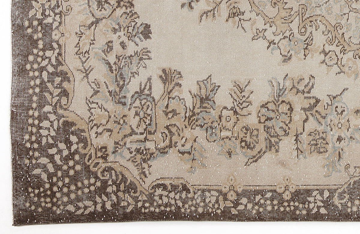 Beige and dark brown rug with a distressed floral medallion pattern and intricate border detail.