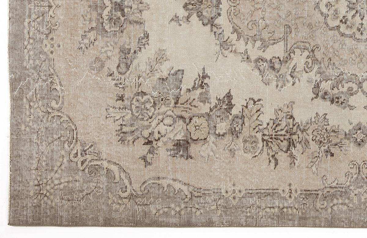 Beige and taupe distressed rug with a faded floral medallion pattern.