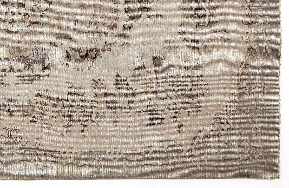 Taupe and beige rug with a distressed traditional floral medallion pattern and a wide decorative border.
