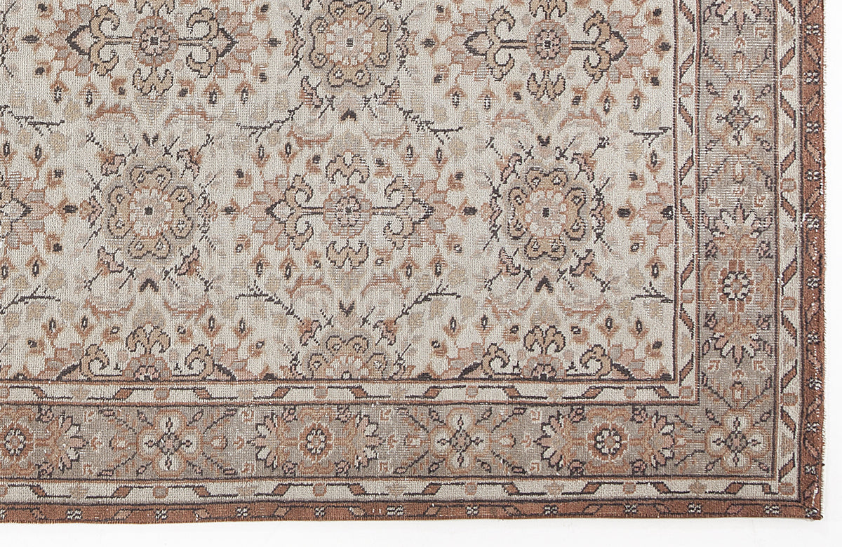 Beige and brown traditional rug with a repeating floral medallion pattern and a decorative geometric border.