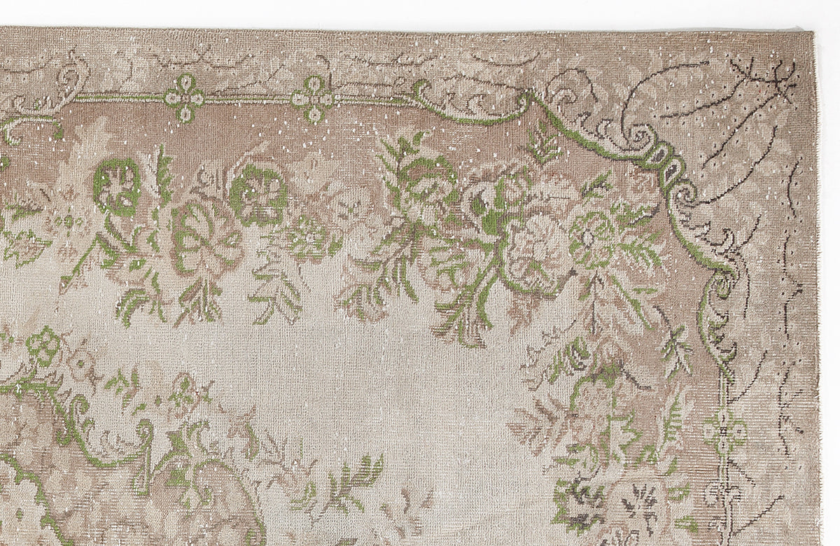 Beige and taupe vintage-style rug with a distressed floral medallion pattern and green accents.
