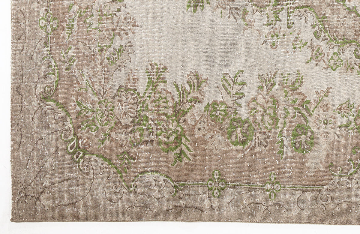 Beige and taupe distressed rug with a green floral border and medallion pattern.