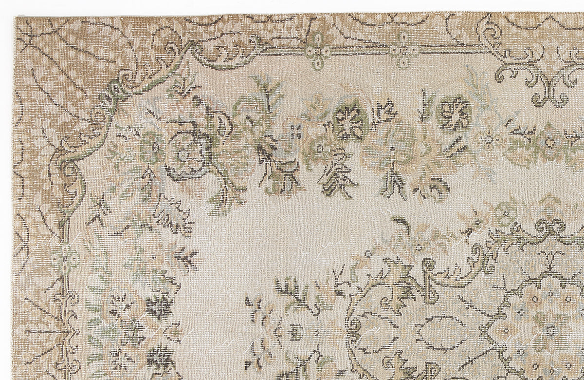 Beige and tan vintage-style rug with a distressed floral medallion pattern in muted green and charcoal accents.