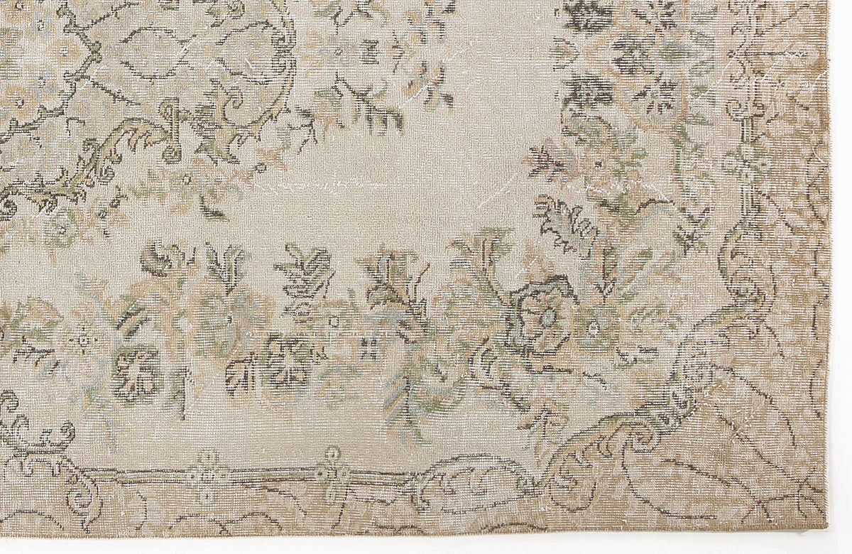 Beige and tan distressed rug with a faded floral medallion pattern and muted green accents.