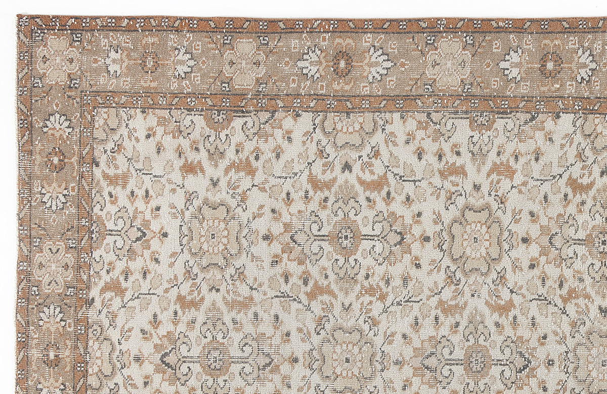 Tan, cream, and grey traditional rug with a distressed floral medallion pattern and a wide decorative border.