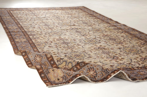 Load image 1 in gallery view. Beige and brown traditional rug with a distressed floral pattern and a wide decorative border on a white background.