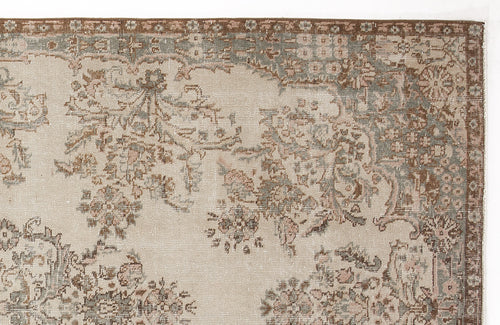 Load image 1 in gallery view. Beige rug with a distressed floral medallion pattern in muted brown, sage green, and soft pink tones.