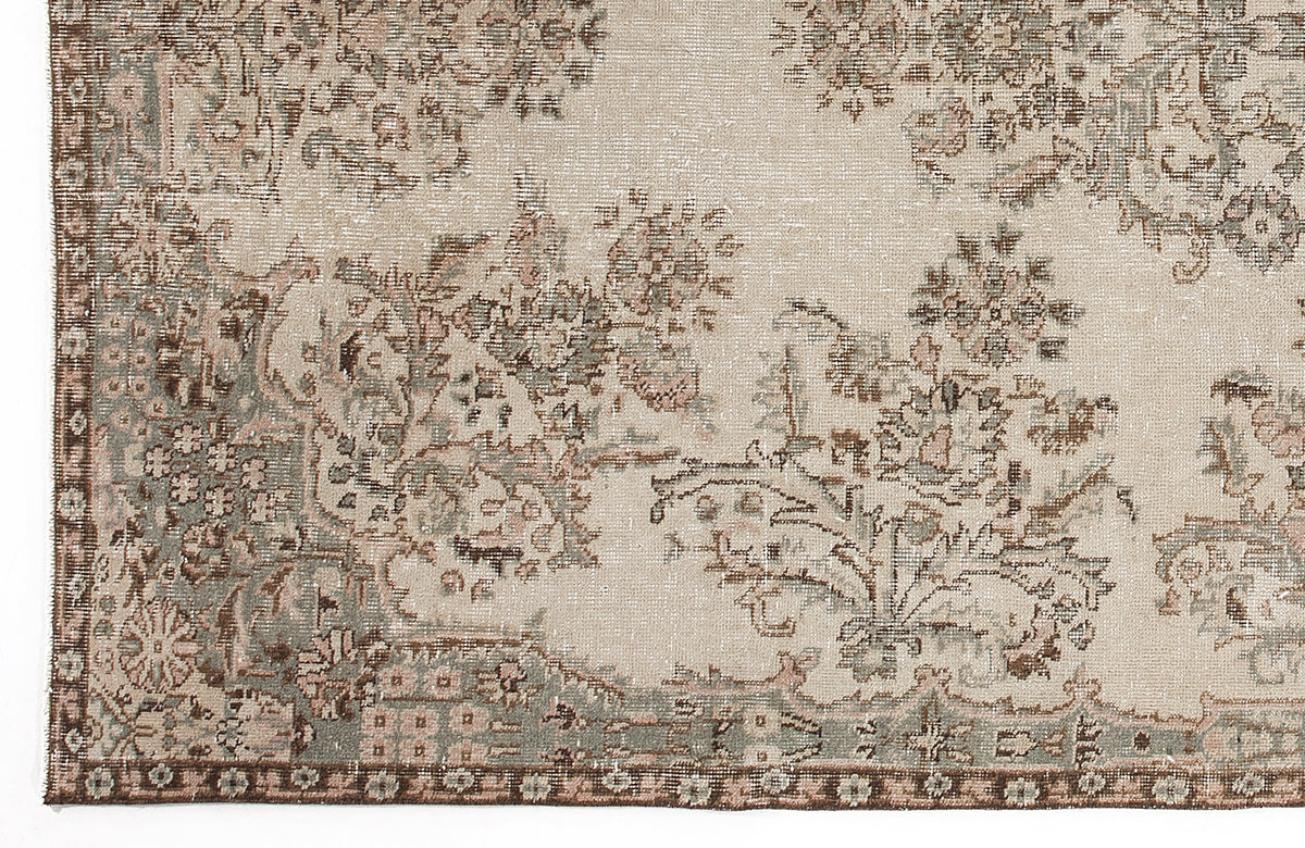 Beige rug with a distressed floral pattern in muted sage green and brown tones.
