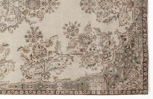 Load image 1 in gallery view. Beige rug with a distressed floral medallion pattern in muted sage green, brown, and soft pink tones.