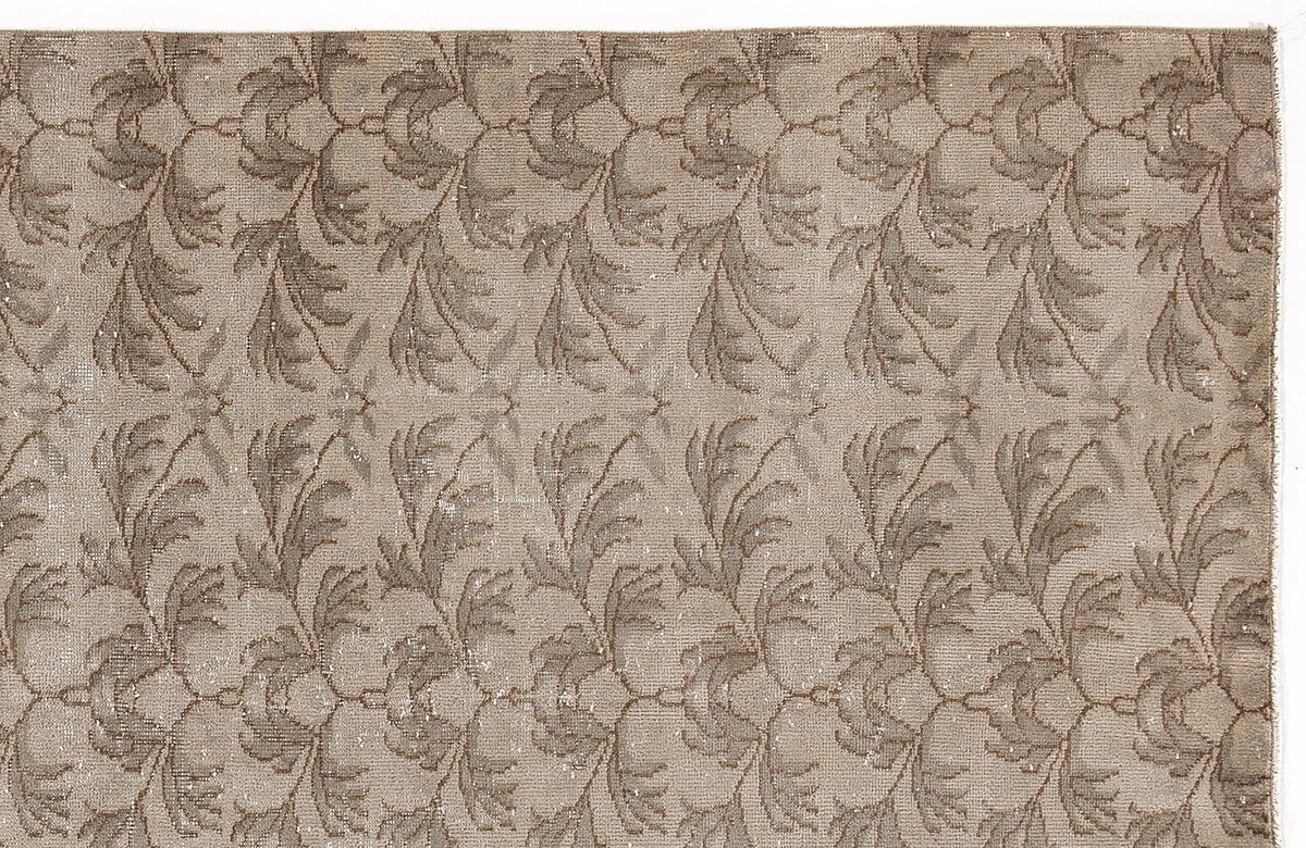 Taupe and beige rug with a repeating distressed floral vine pattern.