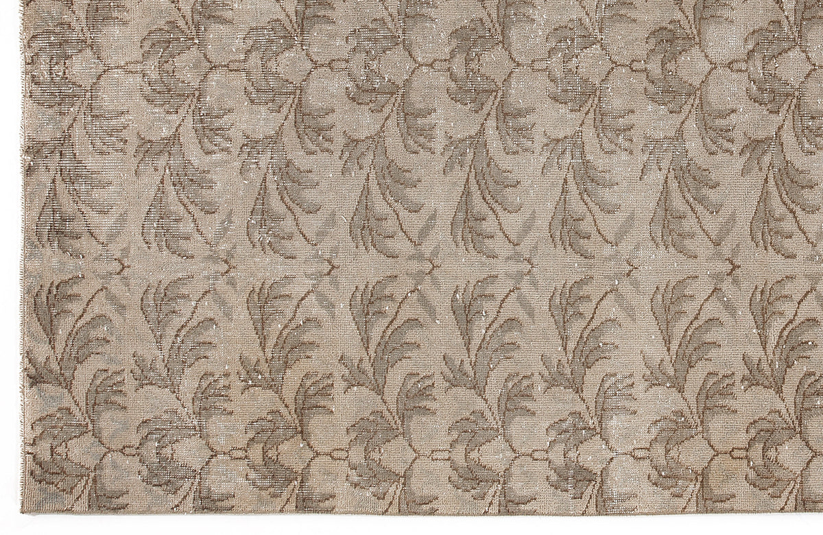 Taupe and beige rug with a repeating distressed botanical leaf pattern.