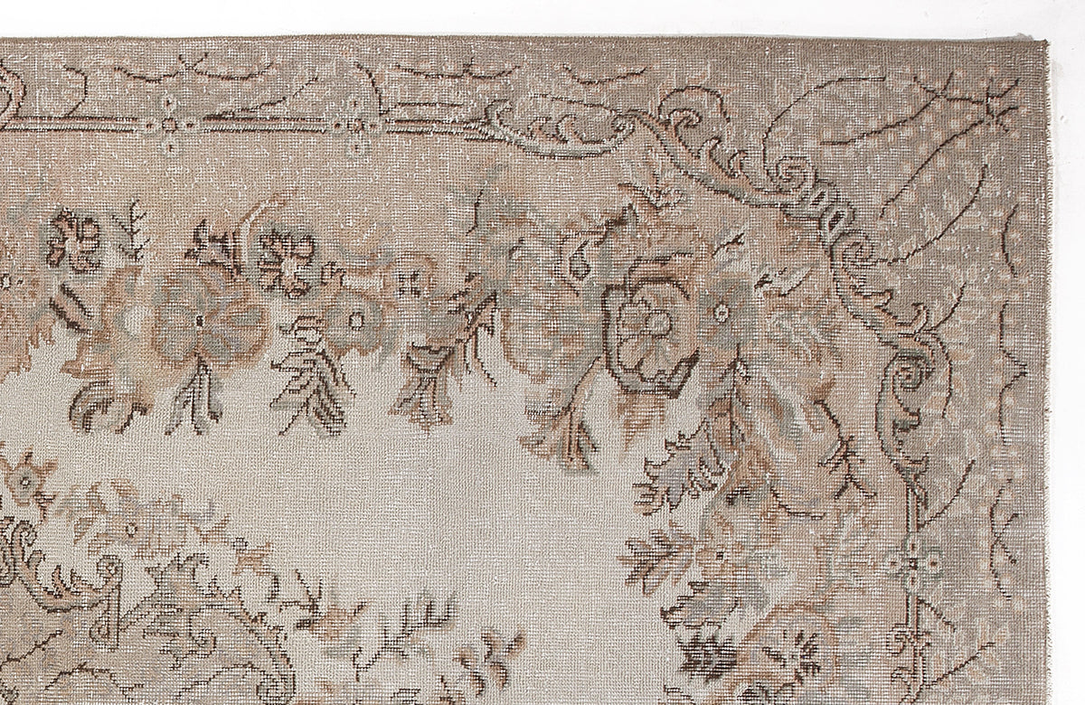 Taupe and beige rug with a distressed floral medallion pattern and ornate border on a white background.