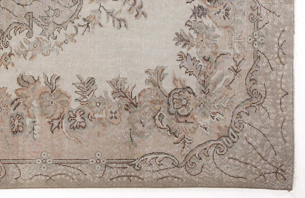 Beige and taupe vintage-style rug with a faded floral medallion pattern and ornate border.