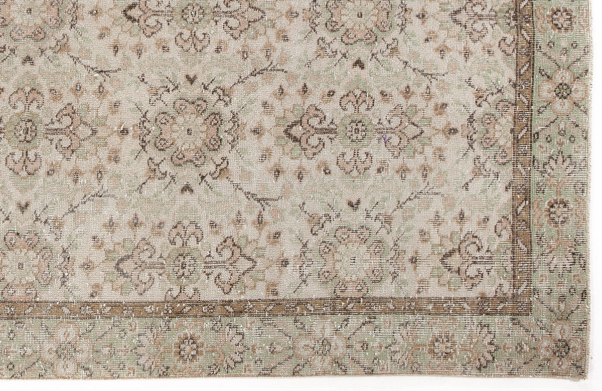 Beige and sage green rug with a distressed traditional floral medallion pattern and a decorative border.