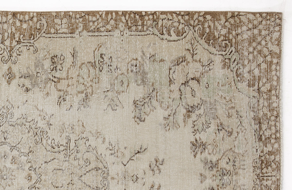 Beige and brown distressed rug with a faded traditional floral medallion pattern on a white background.