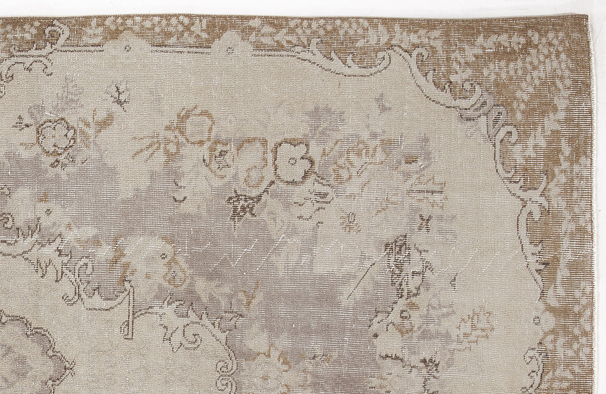 Beige and taupe distressed rug with a faded traditional floral medallion pattern.