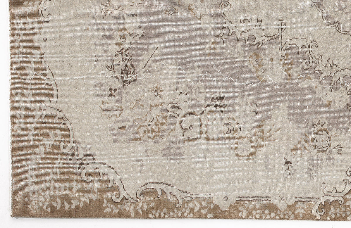 Taupe and cream distressed rug with a faded traditional floral medallion pattern.