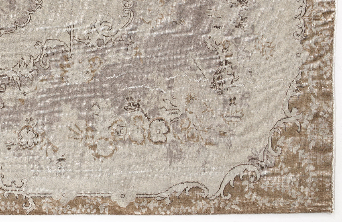 Taupe and beige distressed rug with a faded traditional floral medallion pattern.
