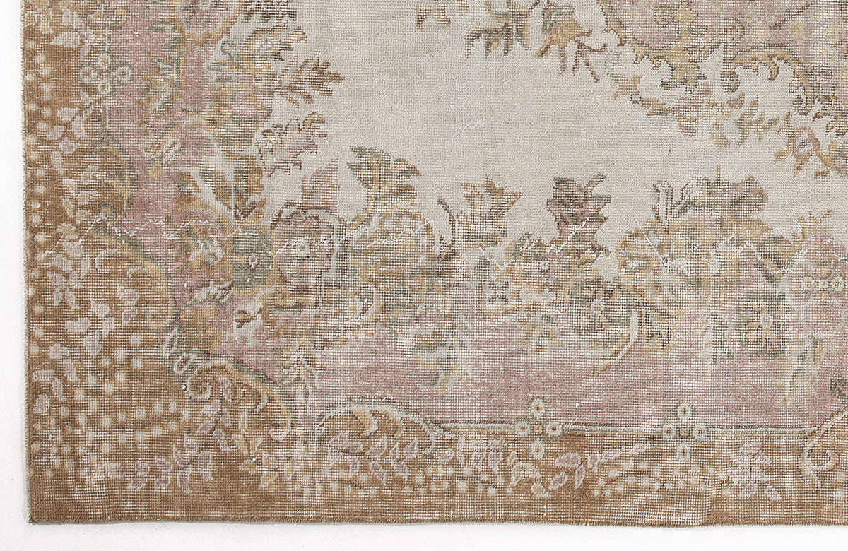 Distressed beige, tan, and muted pink rug with a traditional floral medallion pattern.