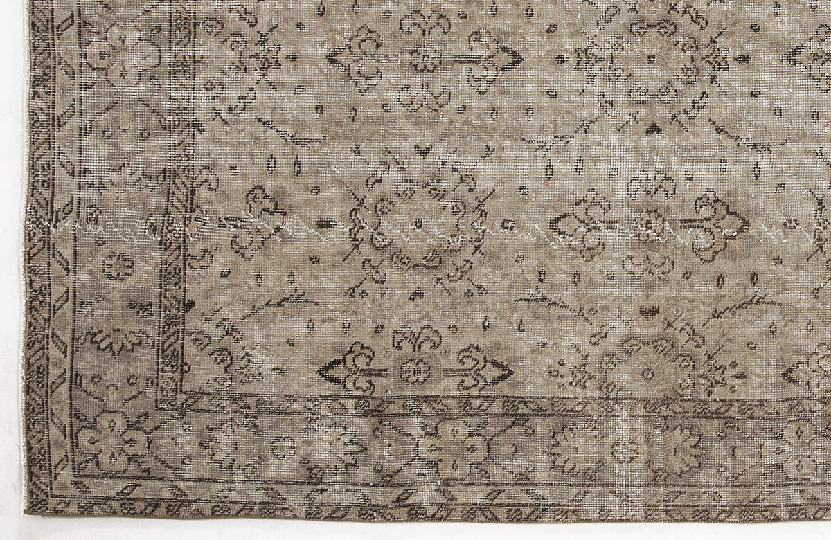 Taupe and dark brown distressed rug with a traditional floral medallion pattern and a geometric border.