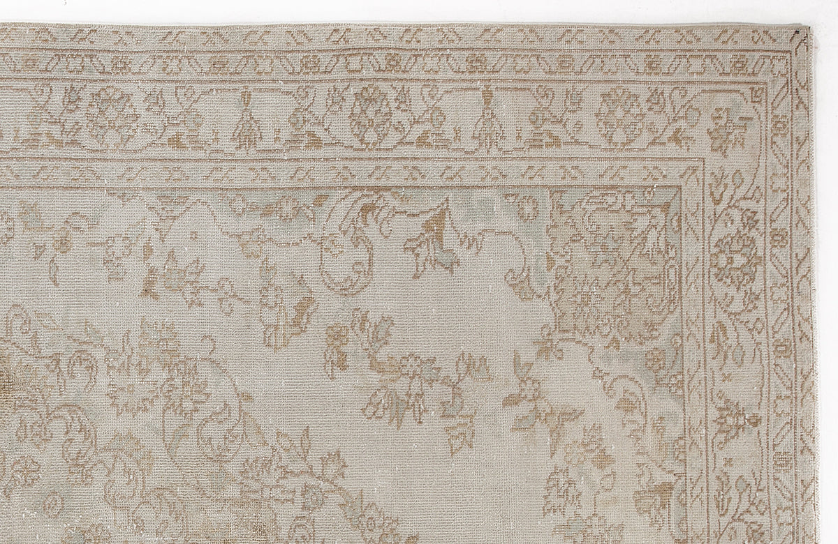 Beige and taupe traditional rug with a faded floral medallion pattern and a detailed geometric border.