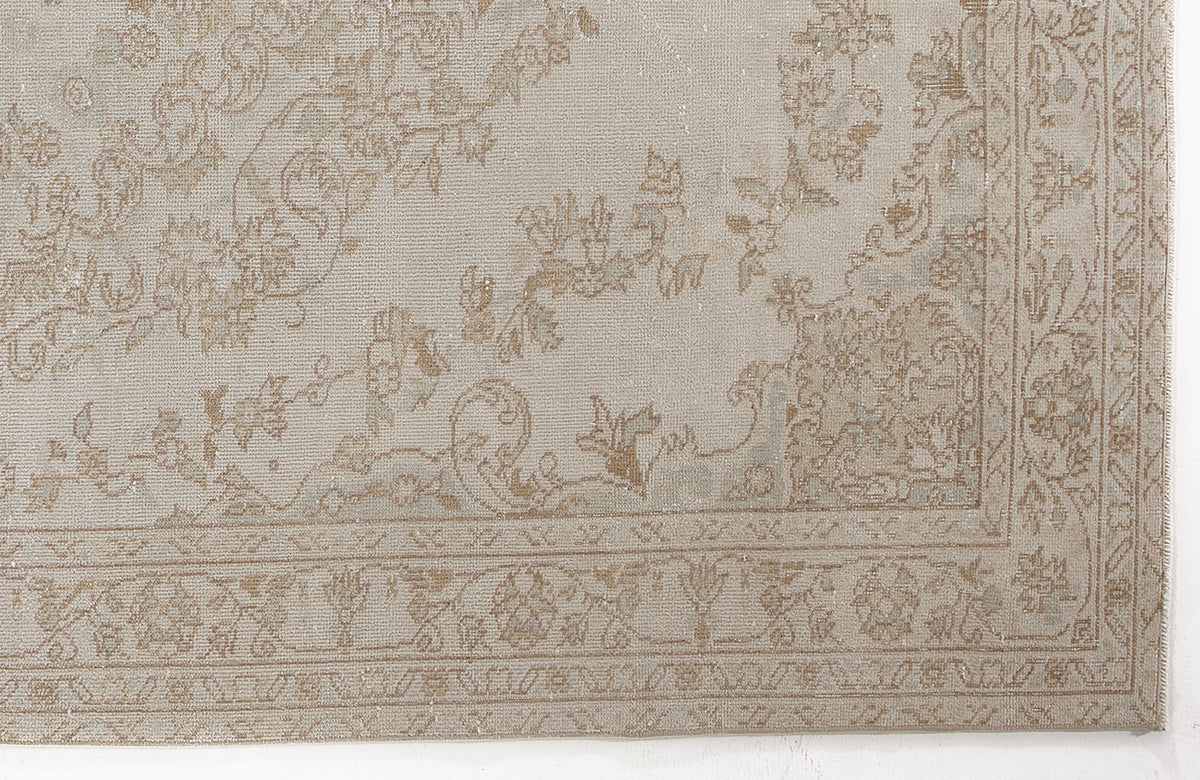Beige and taupe rug with a faded traditional floral pattern and a decorative border.