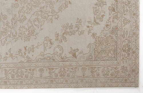 Load image 1 in gallery view. Beige and taupe rug with a faded traditional floral pattern and a decorative border.