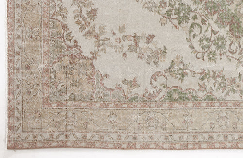 Load image 1 in gallery view. Distressed beige rug with faded sage green and terracotta floral medallion patterns and a decorative border.