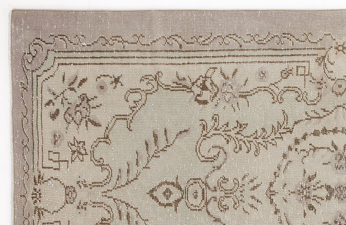 Taupe and beige vintage-style rug with a distressed floral medallion pattern and a decorative border.