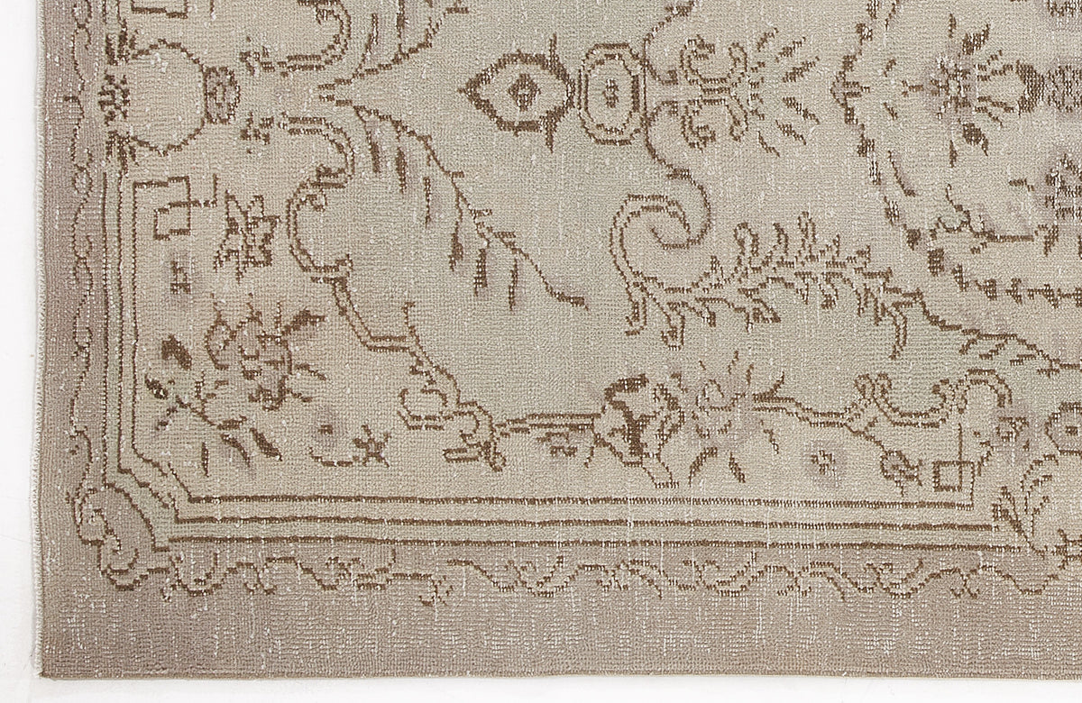Beige and taupe distressed rug with a traditional floral medallion pattern and a decorative border.