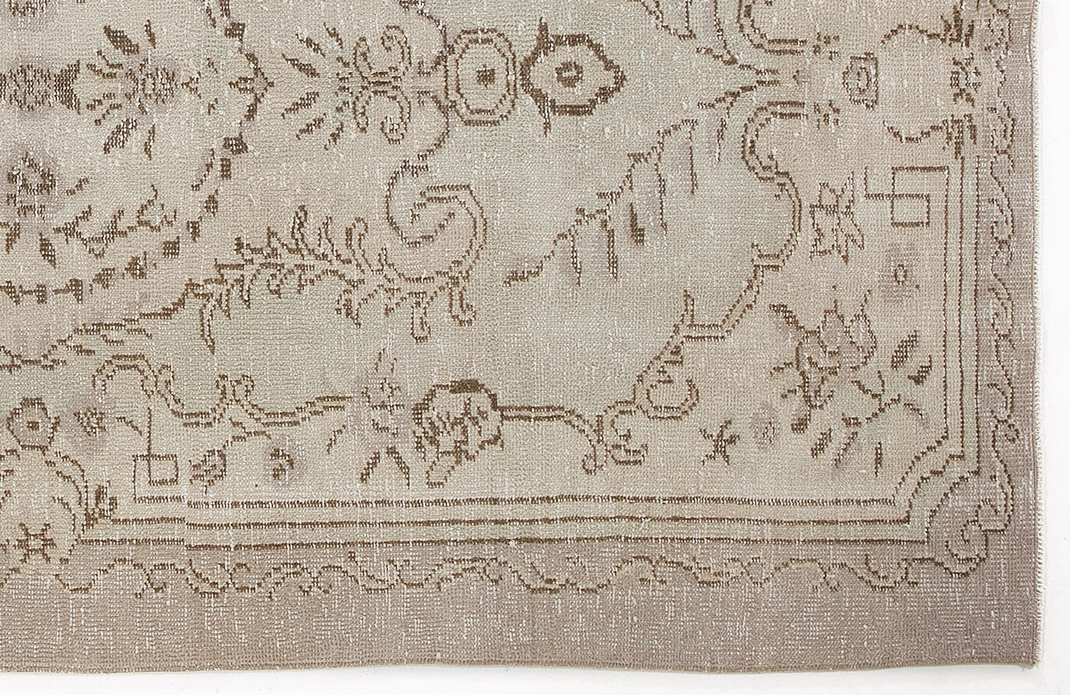Beige and taupe vintage-style rug with a distressed floral medallion pattern and a decorative border.