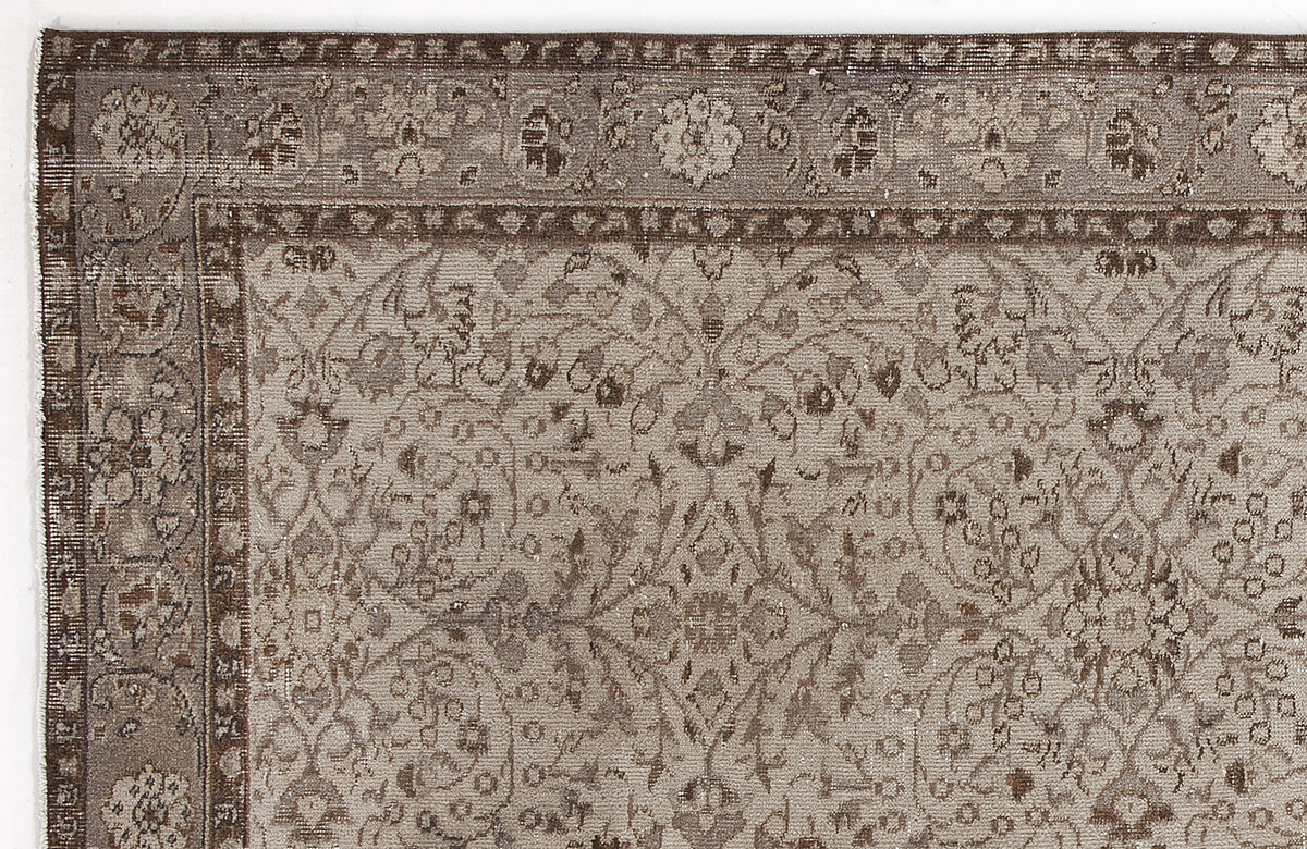 Taupe and brown traditional rug with a distressed floral medallion pattern and a detailed border.