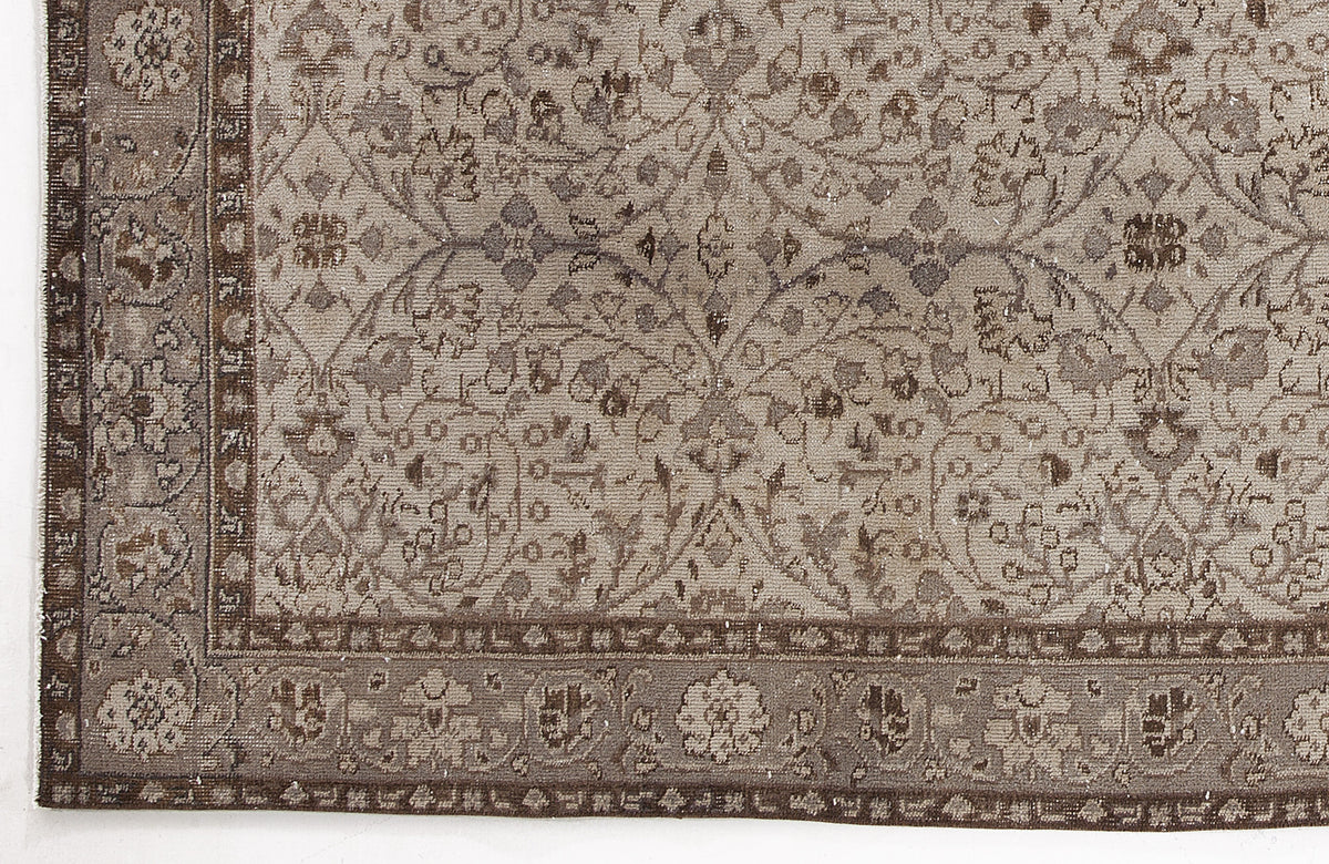 Taupe and brown traditional rug with a distressed floral vine pattern and a detailed geometric border.