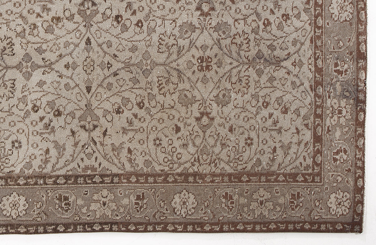 Taupe and brown rug with a traditional floral vine pattern and a decorative border.