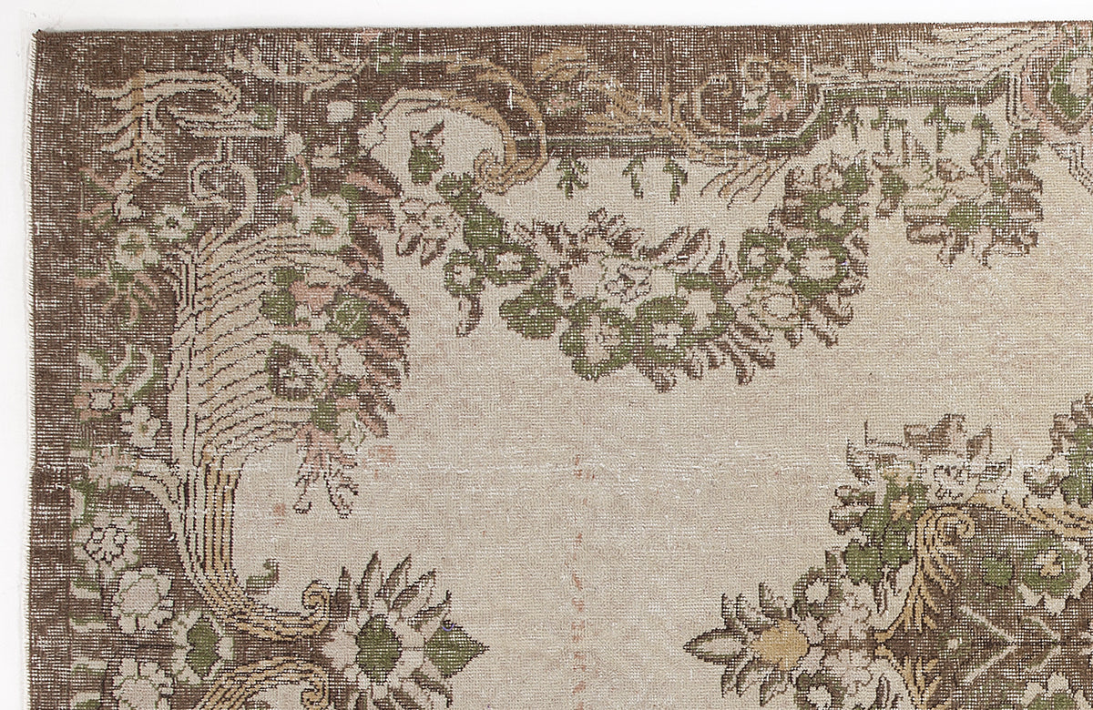 Distressed beige rug with brown and green floral medallion patterns and a wide brown border.