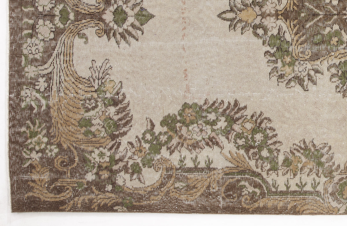 Beige vintage-style rug with a distressed brown and green floral medallion pattern.