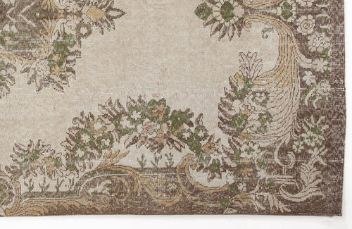 Load image 1 in gallery view. Beige rug with a distressed brown and green floral medallion pattern and ornate border.