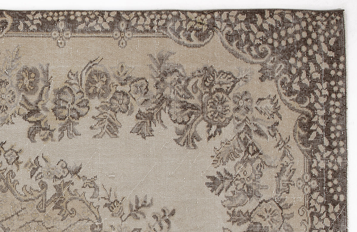 Close-up of a beige and dark brown vintage-style rug featuring a floral medallion pattern and a decorative border.